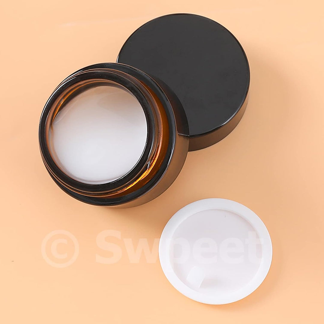 Open amber cosmetic jar with black lid and white inner liner