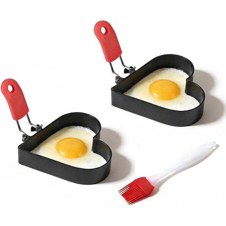 Two black heart-shaped egg rings with red handles and silicone oil brush
