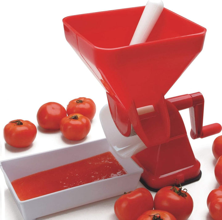Red manual tomato press with tray, pusher and tomatoes